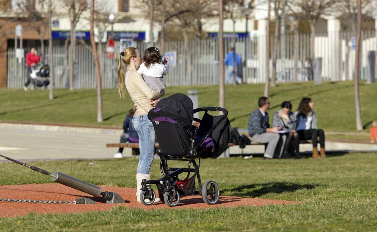 Una mujer pasea por un parque con una niña de corta edad.