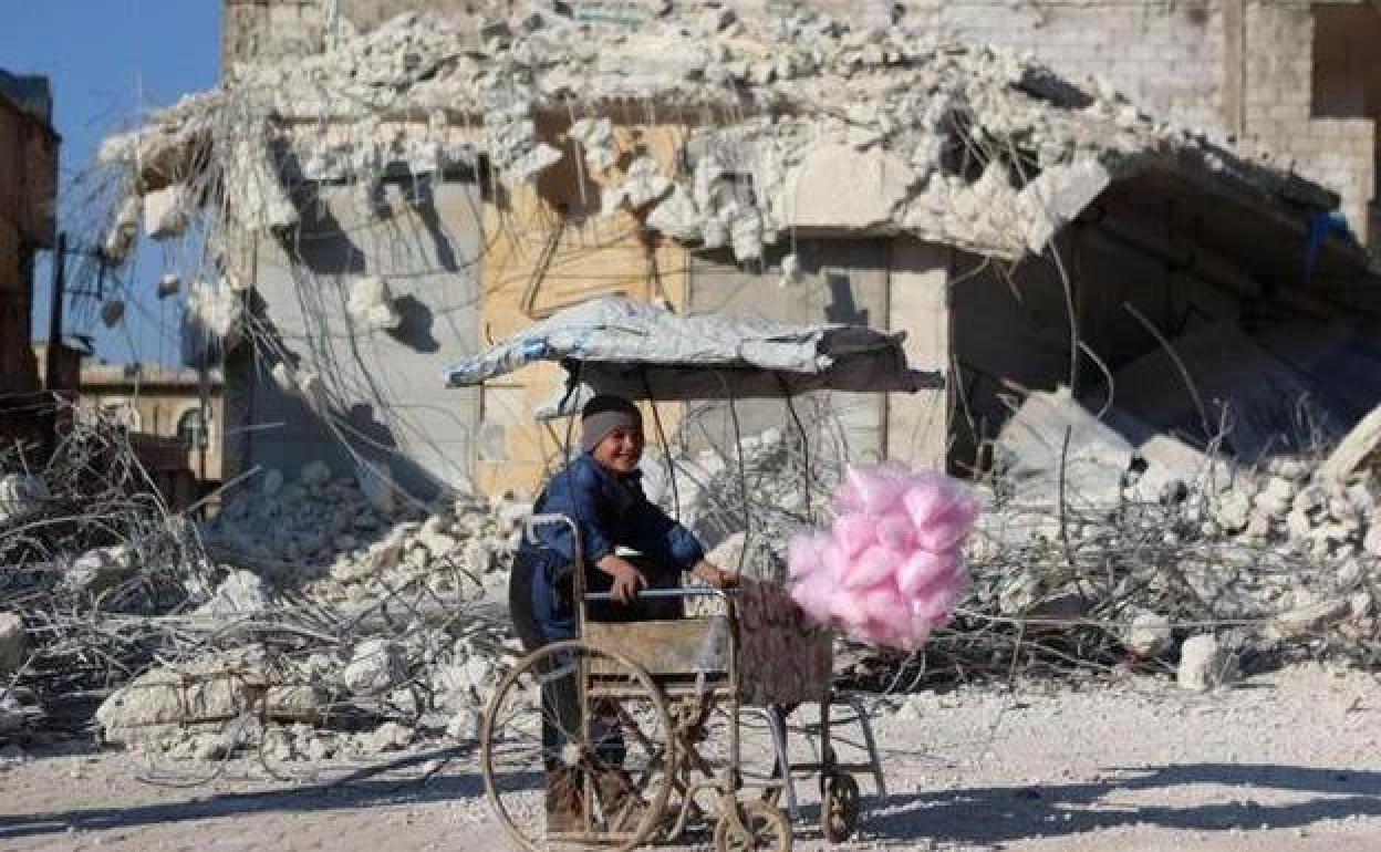 Un niño vende algodón de azúcar junto a la ruinas de la localidad siria de Atarib.