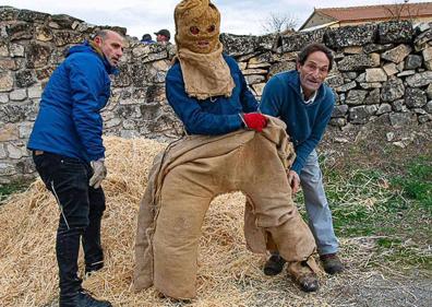 Imagen secundaria 1 - Arriba, participantes en el rito de la Fiesta de la Vaquilla. Abajo, un tripudo es levantado y otro es ayudado para ser vestido. 