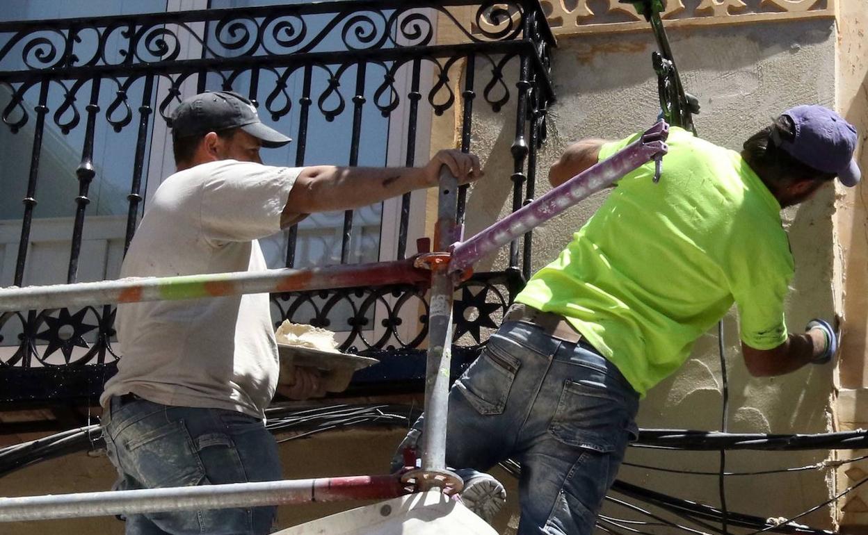 Obreros subidos a un andamio durante los trabajos de rehabilitación de un edificio en Segovia. 