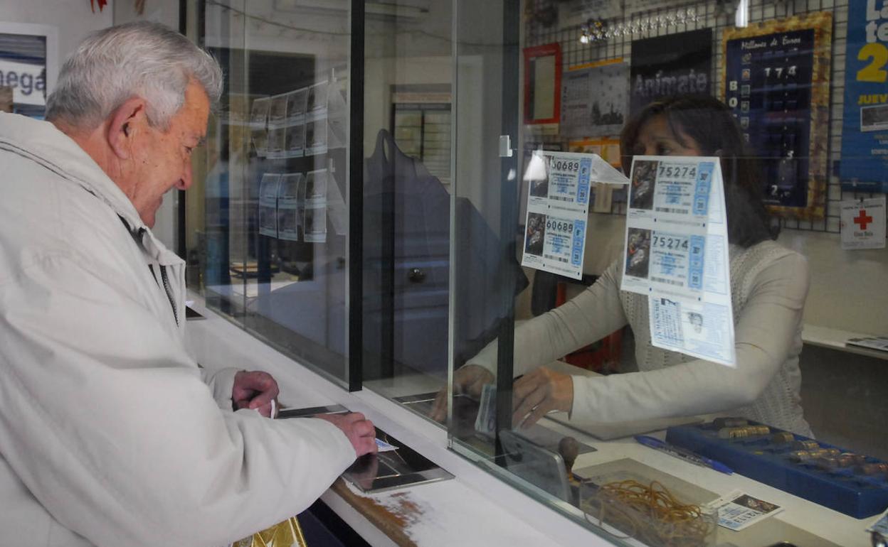 Un hombre compra lotería en una Administración. 