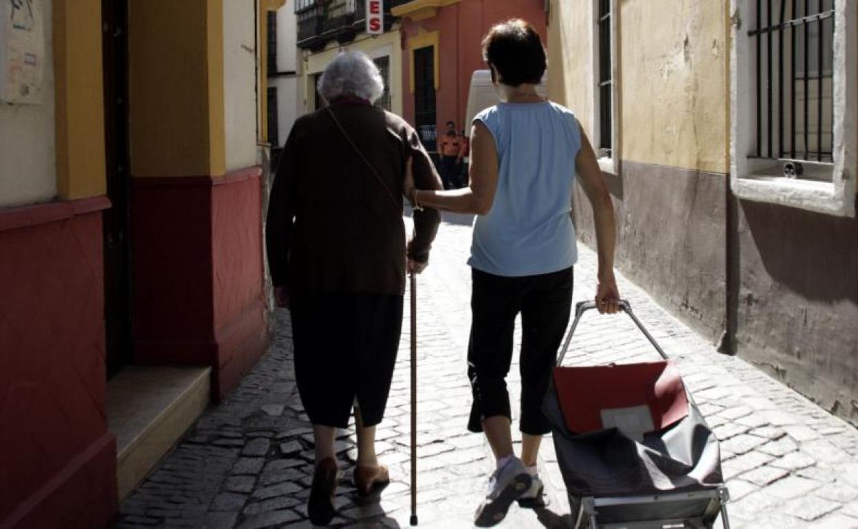 Una cuidadora acompaña a la compra a una anciana. 