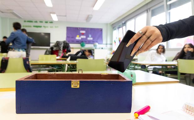 Una alumna del IES Galileo deposita su móvil en una caja antes de entrar en clase. 