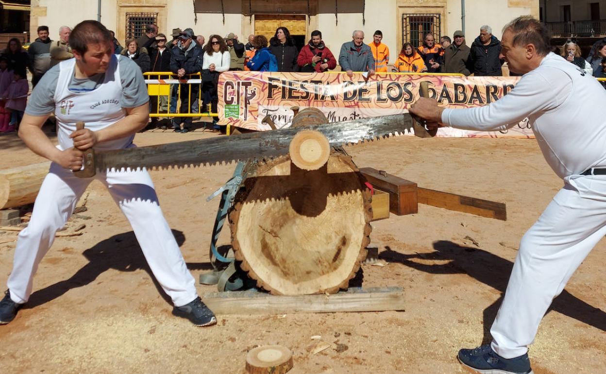 Dos participantes en la exhibición de corta de troncos con sierra, este sábado, en Riaza, con motivo de la Fiesta de los Gabarreros de El Espinar.