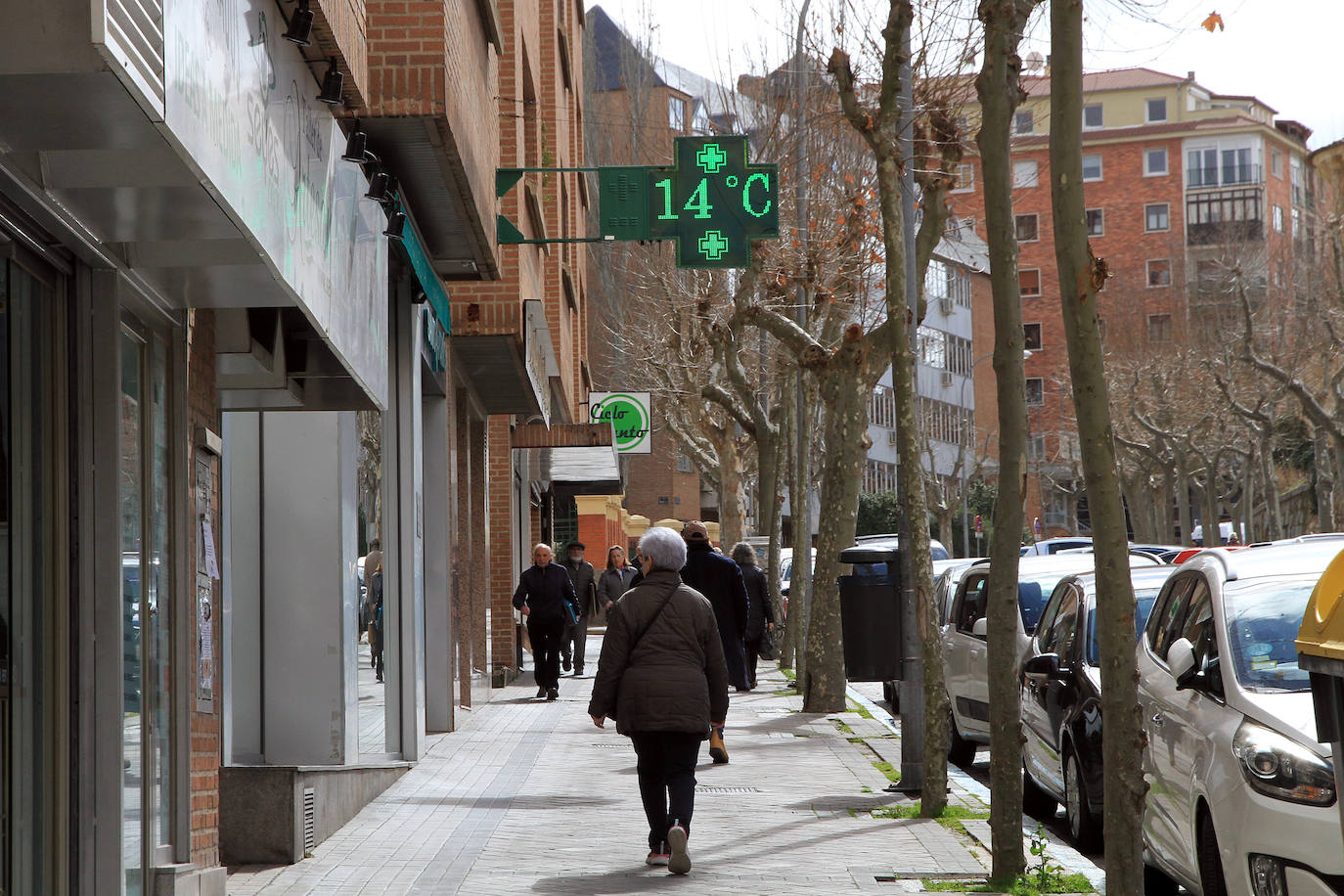 Una mujer pasea por una calle del centro de Segovia a la altura de un termómetro que marca 14 grados de temperatura.