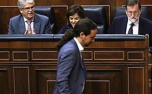 Iglesias pasa por delante del escaño de Rajoy antes de su debate en la moción de censura.