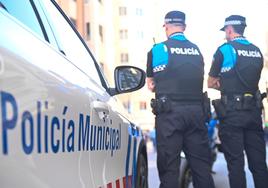 Dos agentes municipales junto a un coche patrulla.