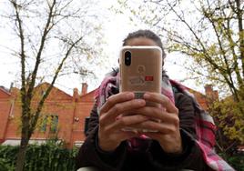 Una joven utiliza su teléfono móvil junto a un instituto de Valladolid capital.