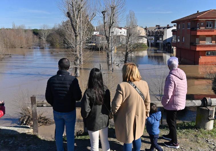 Varios vecinos de Viana de Cega ven la crecida con la calle Río anegada tras dispararse el nivel.