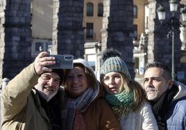 Unos turistas se sacan una foto con el Acueducto de Segovia al fondo.