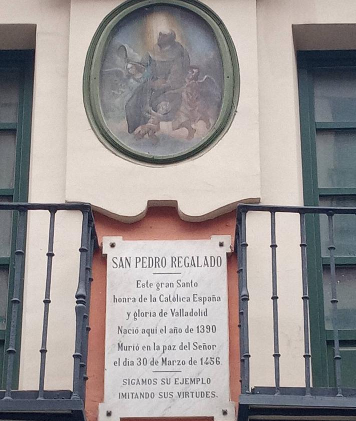 Imagen secundaria 2 - El pavimiento negro, y una placa, dan noticia de que por debajo está el cauce del Esgueva; azulejo del siglo VXIII y detalle que conmemora el nacimiento de San Pedro Regalado