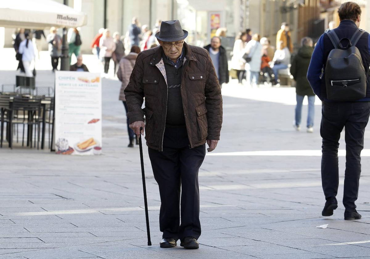 Un hombre pasea con su bastón por las calles del centro de Segovia.