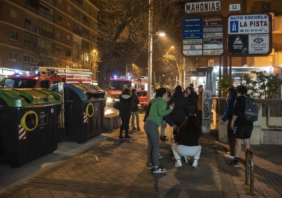 Vecinos y transeúntes en la calle comentan lo sucedido mientras los bomberos ventilan las estancias afectadas por el incendio y el humo.