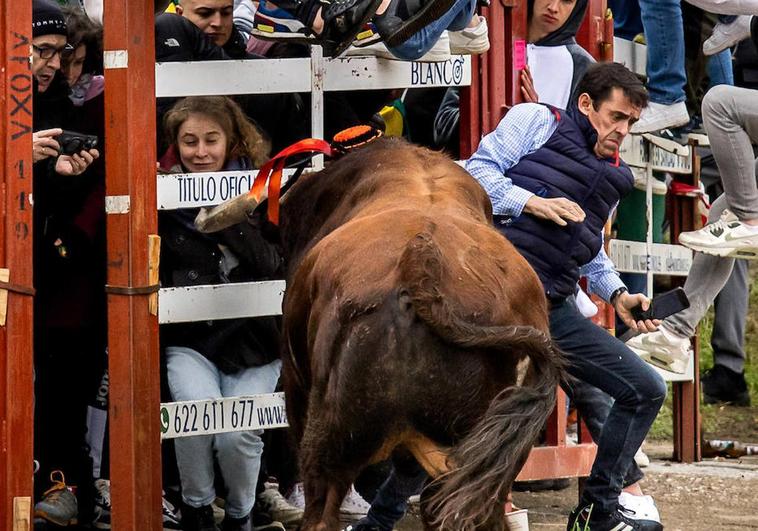 Un hombre intenta evitar la embestida del toro.