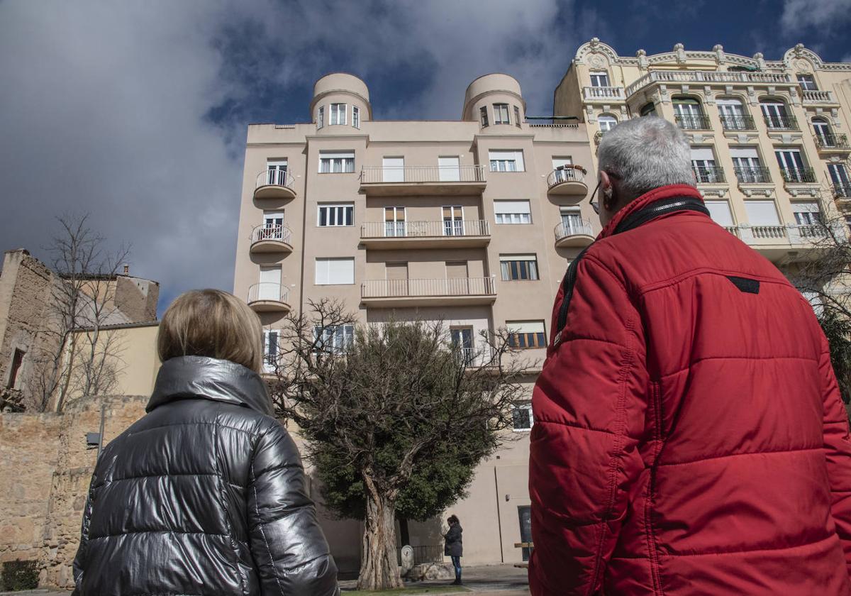 Dos personas observan la fachada de un edificio del movimiento moderno desde el paseo del Salón.