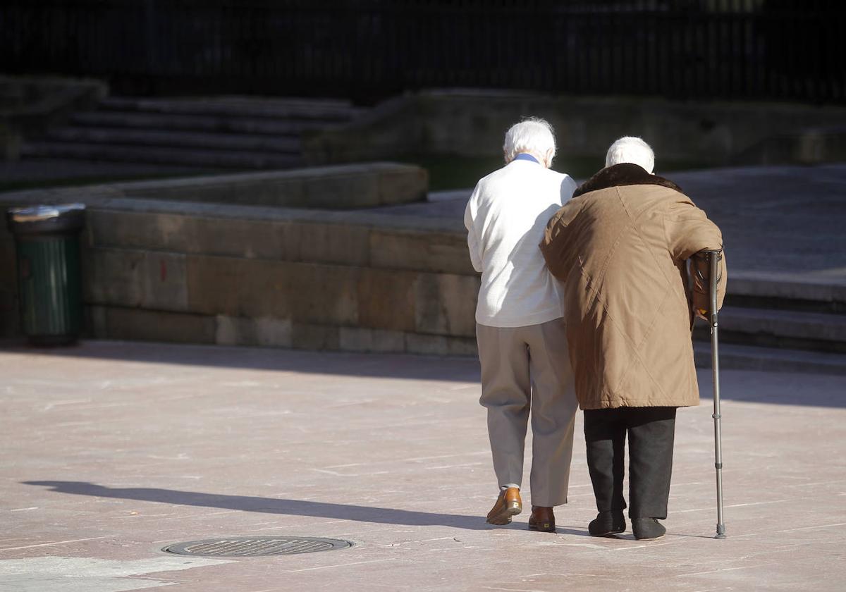 Dos personas mayores caminan por la calle.