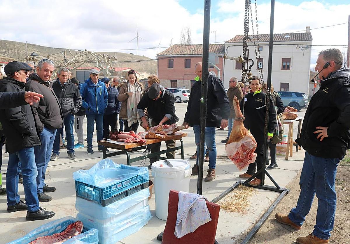 Roberto Román pesa uno de los jamones del cerdo y comenta los detalles al público.