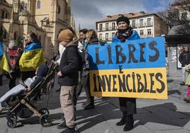 Una niña con la bandera de Ucrania deja un donativo en una urna en la concentración de este sábado en Segovia.