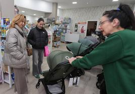 Una dependienta de la tienda Dulce Bebé muestra sillas de paseo a dos clientas.