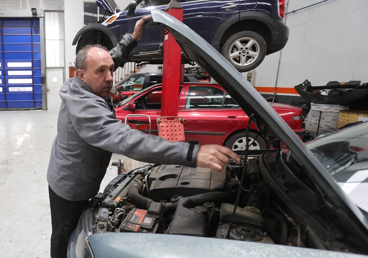 Miguel Ángel Garrido levanta el capó de un coche.