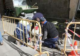 Unos operarios arreglan unas baldosas en la Calle Real de Segovia esta semana.