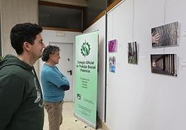Dos personas observan la exposición de Trabajo Social en la Biblioteca Pública.