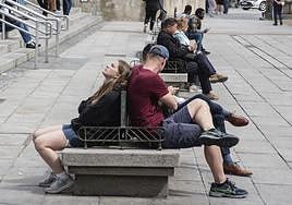 Dos jóvenes en pantalón corto toman el sol este jueves, en la plaza del Azoguejo.