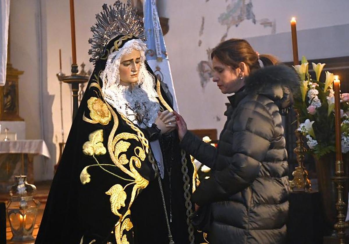 Una mujer se acerca a la imagen de la Virgen.