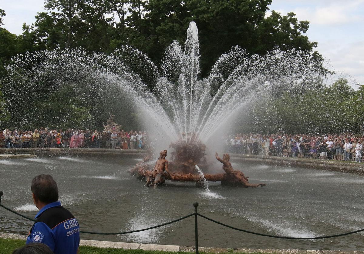 Cientos de visitantes se agolpan alrededor de una de las fuentes de los Jardines de La Granja en pleno funcionamiento.