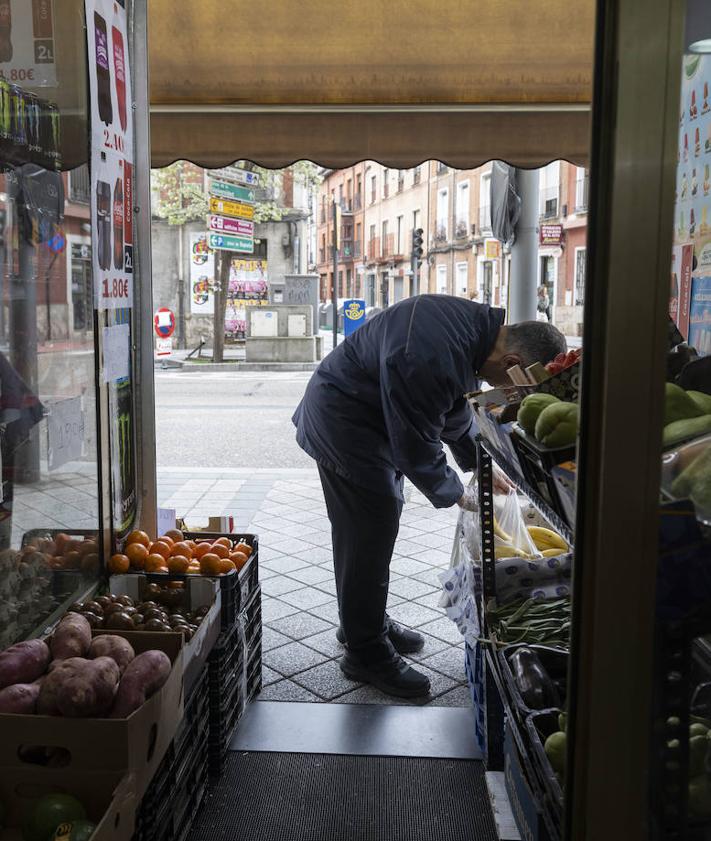 Imagen secundaria 2 - Enu, en su tienda, pesa en la báscula los plátanos que un cliente le ha comprado.