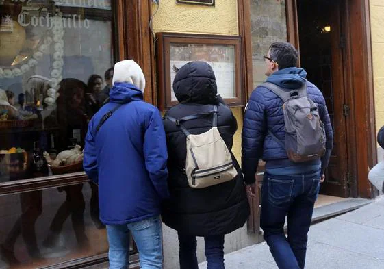 Un grupo de turistas revisa la carta de un restaurante de la ciudad de Segovia.