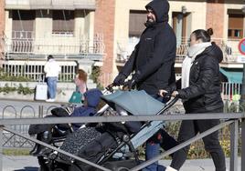 Dos personas pasean a niños pequeños en carrito por el centro de Segovia.