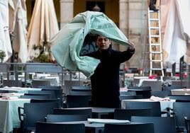 Un trabajador de hostelería coloca el mantel en una terraza, en una imagen de archivo.