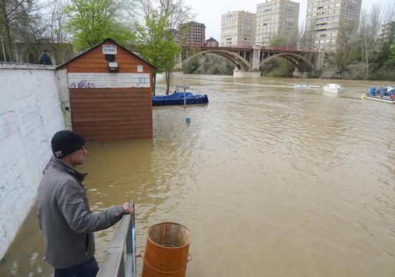 Un hombre observa los paseos anegados del Pisuerga antes del puente de Poniente.