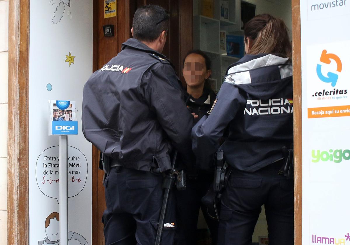 Agentes de la Policía Nacional de Segovia hablan con una persona en una tienda.