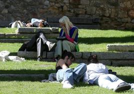 Jóvenes tumbadas toman el sol bajo los arcos del Acueducto, este miércoles.