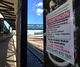 Cartel de la Plataforma por el Soterramiento, al paso de un tren bajo la pasarela peatonal de Las Norias.