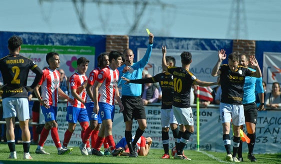 El colegiado muestra una amarilla a un jugador visitante.