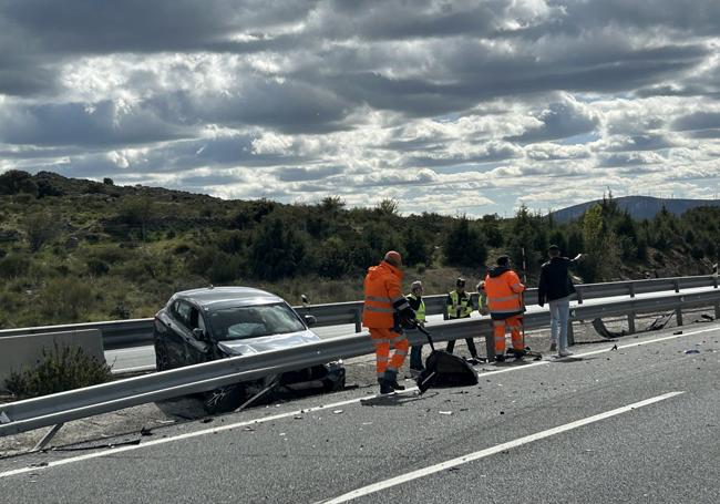 Operrios limpian los restos de un coche accidentado.