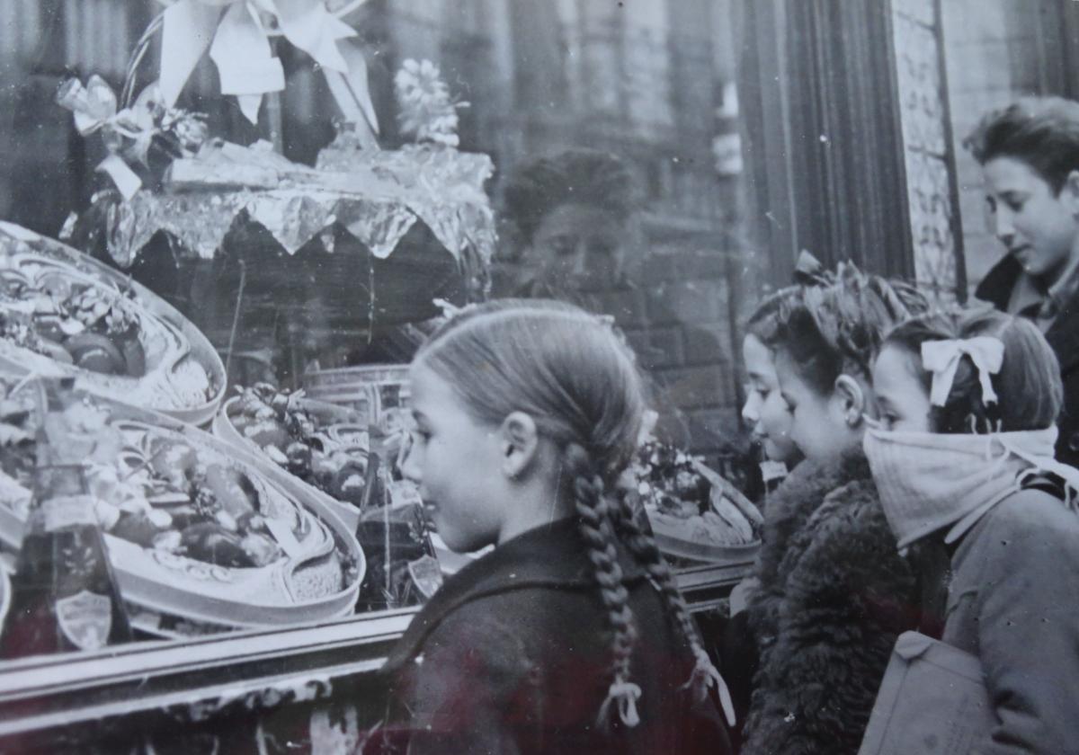 Unos niños observan las cajas de anguilas en el escaparate del Horno Francés en Navidad.