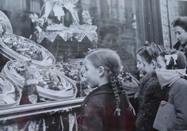 Unos niños observan las cajas de anguilas en el escaparate del Horno Francés en Navidad.