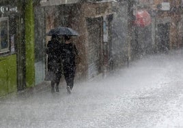 Dos personas se refugian bajo el paraguas del granizo, este domingo en Segovia.