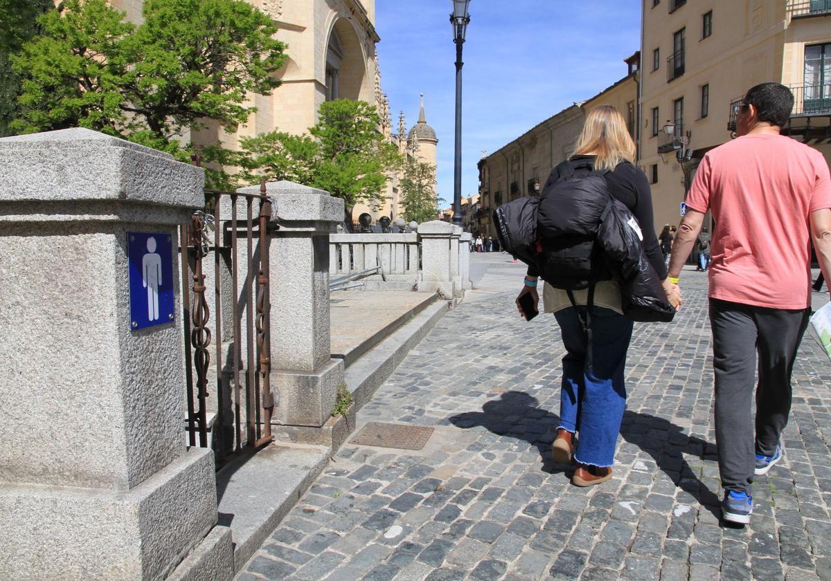 Una pareja de turistas pasea junto a los baños públicos de la Plaza Mayor, actualmente cerrados.