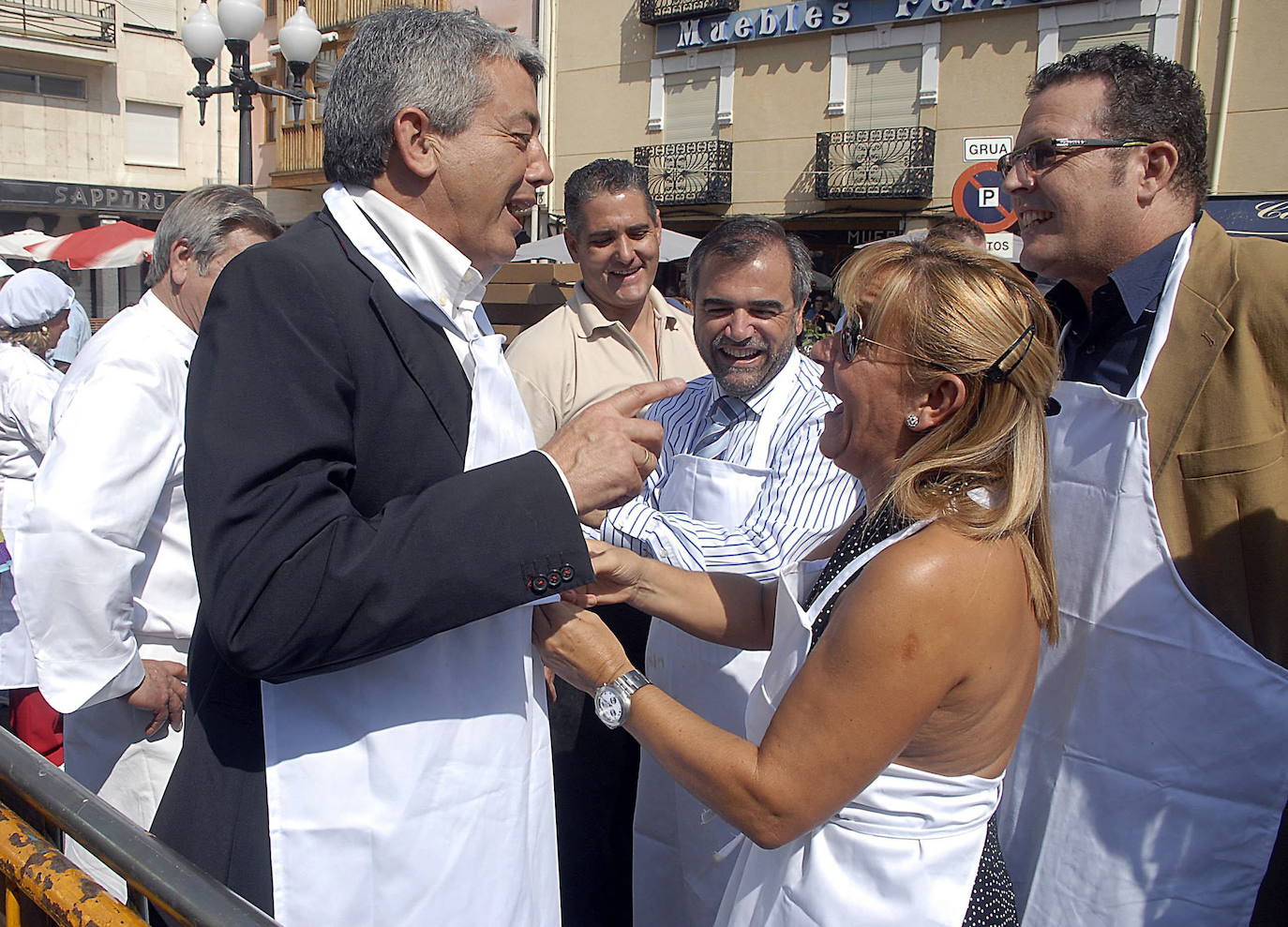 2007. Isabel Carrasco bromea mientras le ajusta el mandil al secretario provincial del PSOE, Miguel Martínez, en presencia del alcalde de La Bañeza, José Miguel Palazuelo (c), durante la tradicional alubiada de La Bañeza (León).