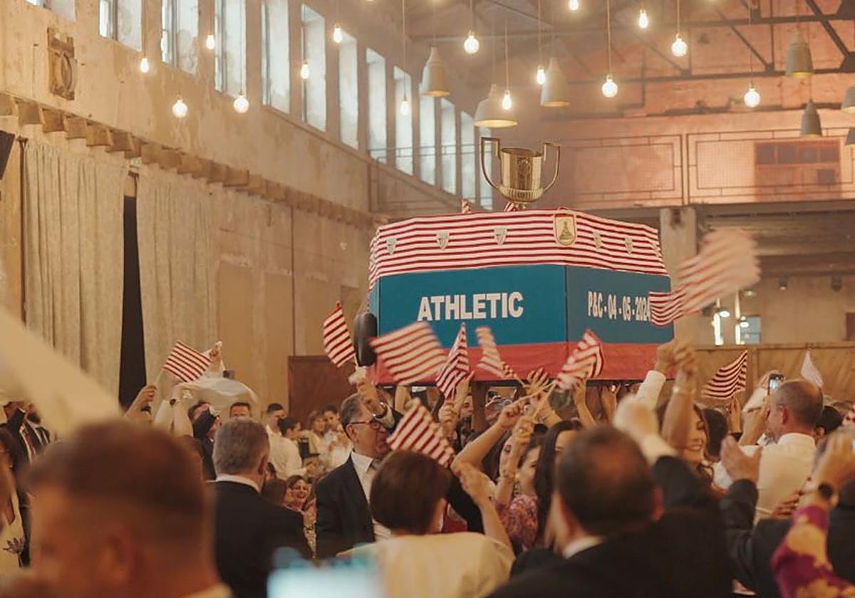 Las amigas de la novia entran al banquete con la gabarra del Athletic de cartón.