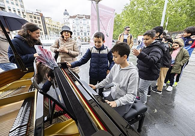 Varios niños observan como un compañero toca el piano.