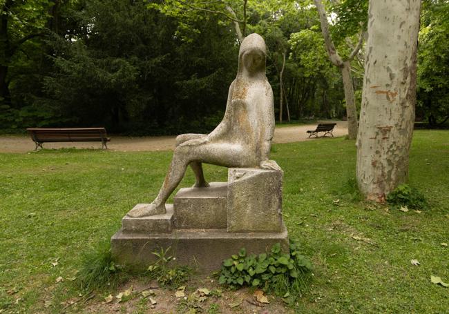 Muchacha sentada mirando a un caracol, escultura de cemento.