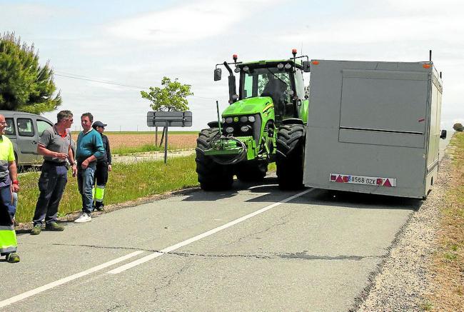 Vecinos observan cómo tratan de pasar por la SG-322, en Muñopedro, un tractor que se cruza con otro vehículo.