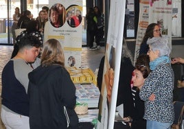 Unos jóvenes se interesan por algunas de las asociaciones presentes en la feria del Voluntariado, este lunes, en la UVA.