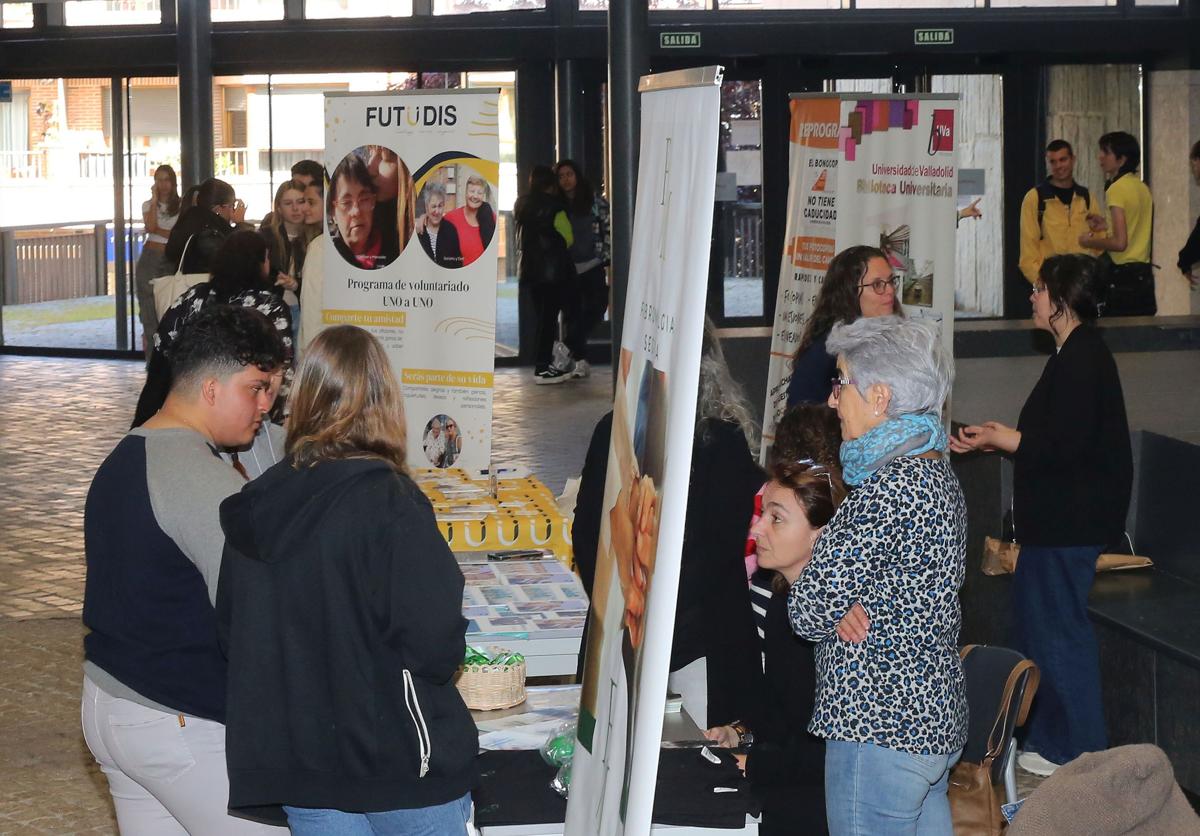 Unos jóvenes se interesan por algunas de las asociaciones presentes en la feria del Voluntariado, este lunes, en la UVA.